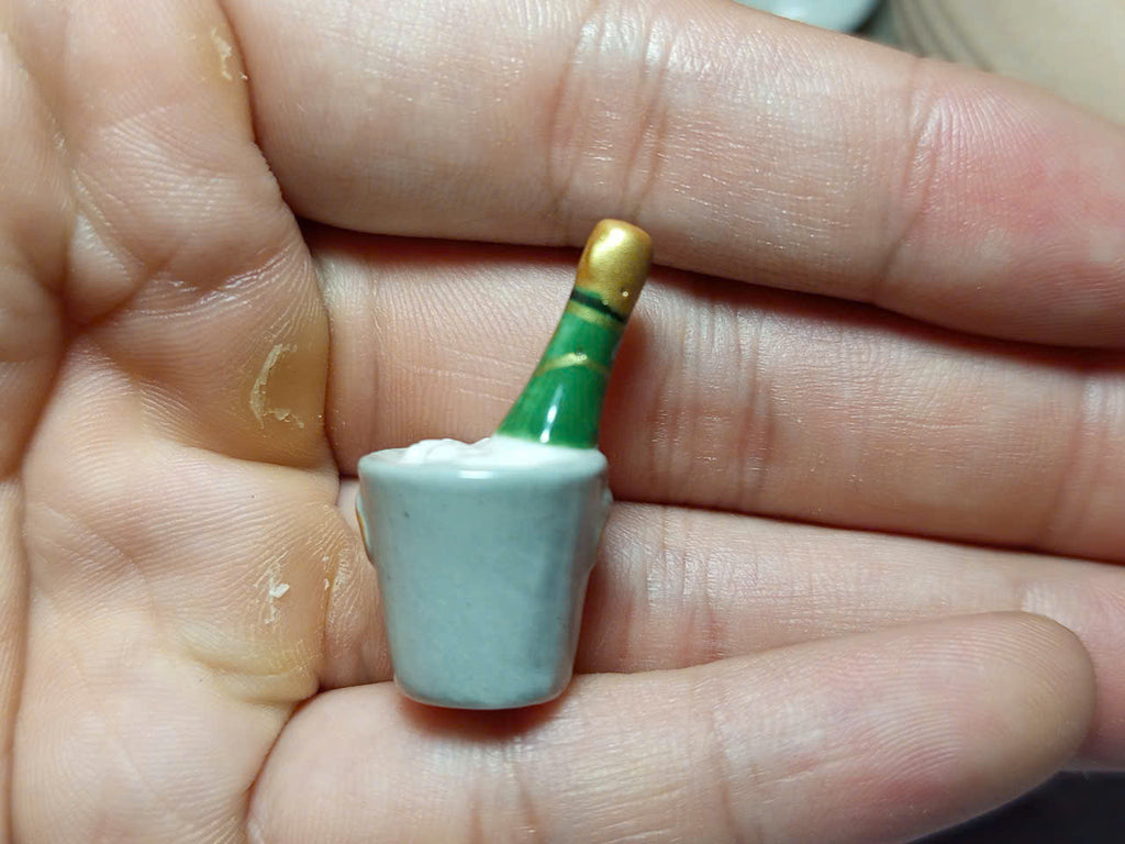 Back view of miniature green bottle and pale ceramic ice bucket fève