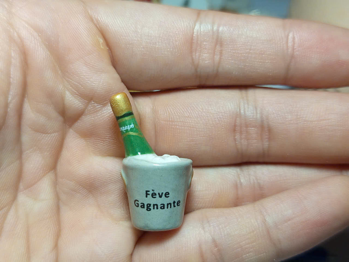 Fève Gagnante champagne-style bottle miniature displayed on white satin